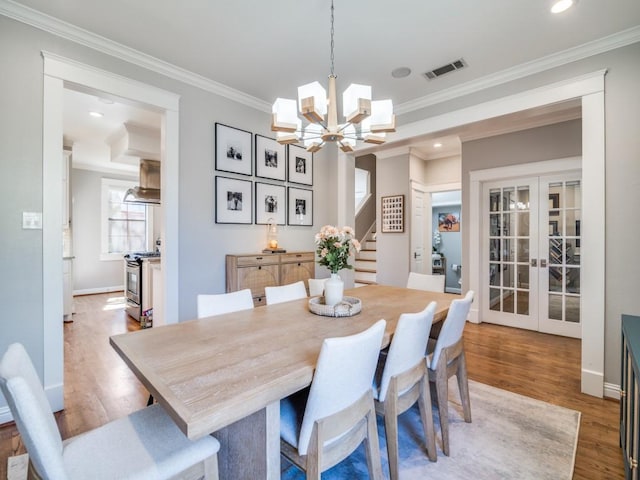 dining space featuring visible vents, ornamental molding, wood finished floors, french doors, and stairs