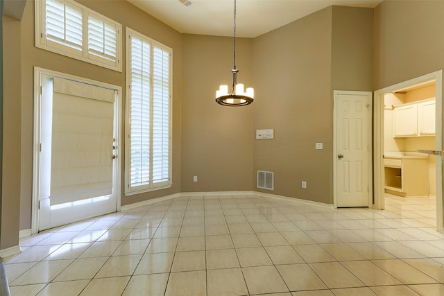 entryway with light tile patterned flooring, visible vents, a high ceiling, and a notable chandelier