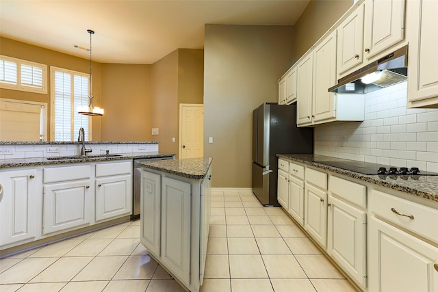 kitchen with under cabinet range hood, a sink, freestanding refrigerator, light tile patterned flooring, and black electric stovetop