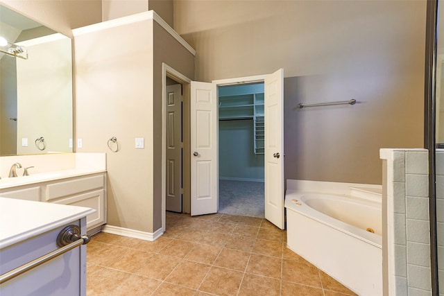 full bathroom with vanity, tile patterned flooring, baseboards, a bath, and a spacious closet