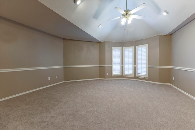 empty room with vaulted ceiling, carpet flooring, baseboards, and ceiling fan