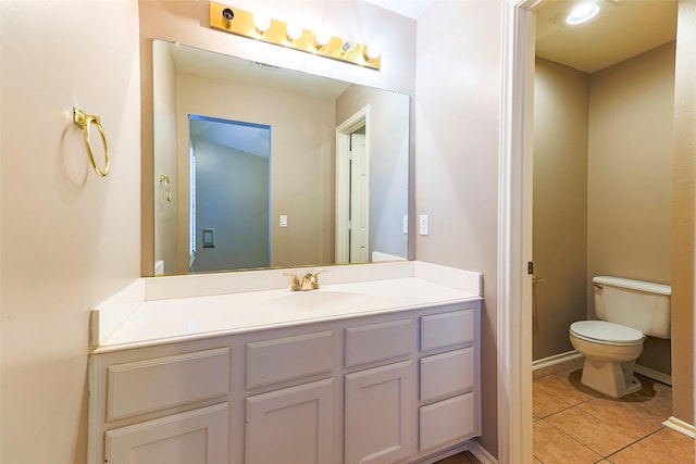 bathroom with tile patterned flooring, toilet, vanity, and baseboards