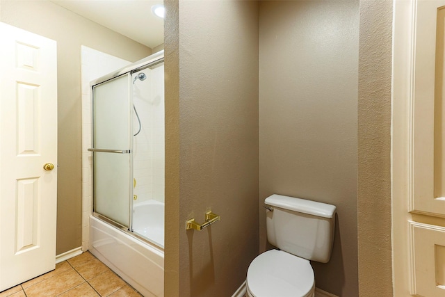 bathroom with tile patterned flooring, toilet, and combined bath / shower with glass door