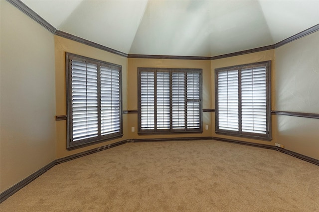 carpeted empty room featuring baseboards, lofted ceiling, and crown molding