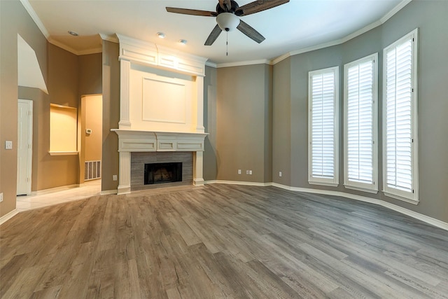 unfurnished living room featuring visible vents, a healthy amount of sunlight, ornamental molding, and a fireplace