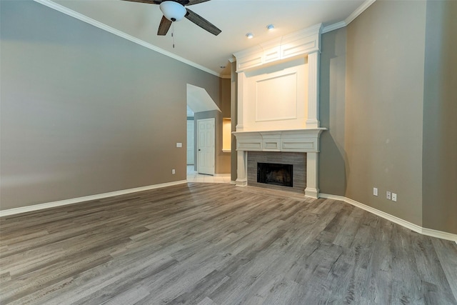 unfurnished living room with a fireplace, crown molding, baseboards, and wood finished floors