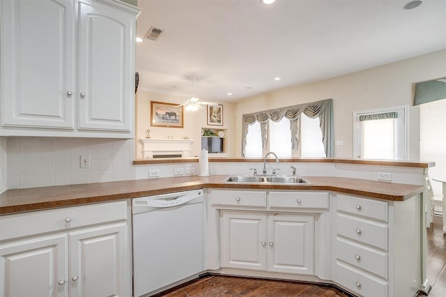 kitchen with visible vents, a peninsula, white dishwasher, a sink, and decorative backsplash