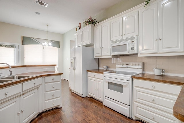 kitchen featuring visible vents, a sink, tasteful backsplash, white appliances, and dark wood-style flooring