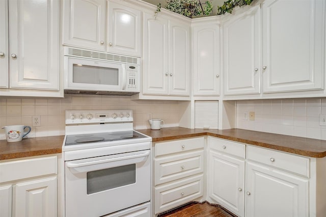 kitchen with decorative backsplash, white appliances, and dark countertops