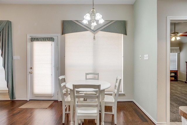 dining area featuring ceiling fan with notable chandelier, dark wood-style floors, and baseboards