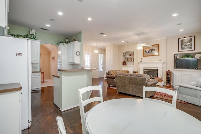 dining room featuring arched walkways, visible vents, dark wood finished floors, and a glass covered fireplace