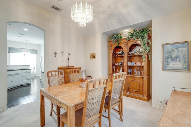 dining area with visible vents, arched walkways, an inviting chandelier, and vaulted ceiling