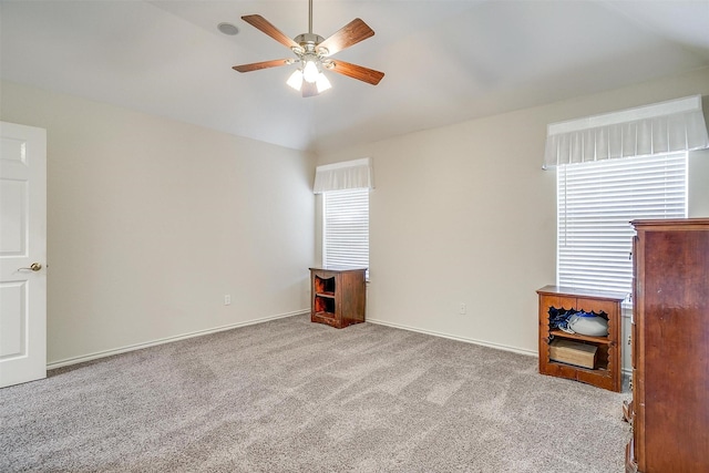 carpeted spare room featuring baseboards, lofted ceiling, and a ceiling fan