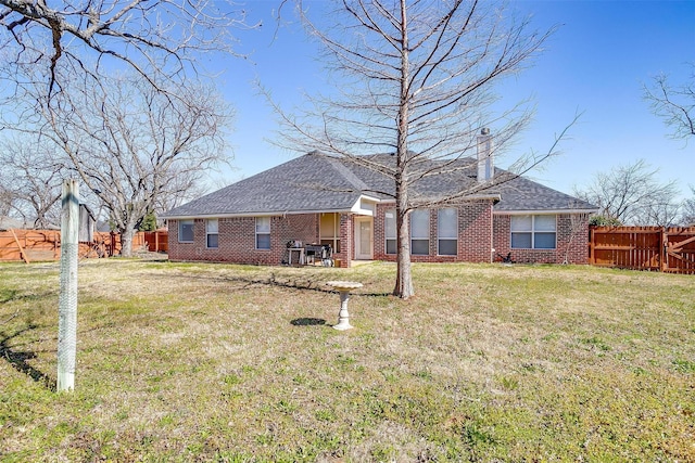 rear view of house with a chimney, fence, brick siding, and a lawn