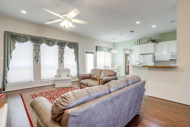 living area featuring dark wood-type flooring, recessed lighting, ceiling fan with notable chandelier, and visible vents