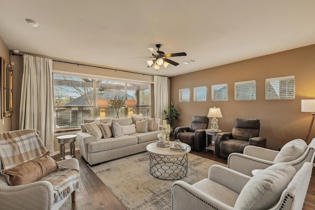 living area with visible vents, a ceiling fan, and wood finished floors