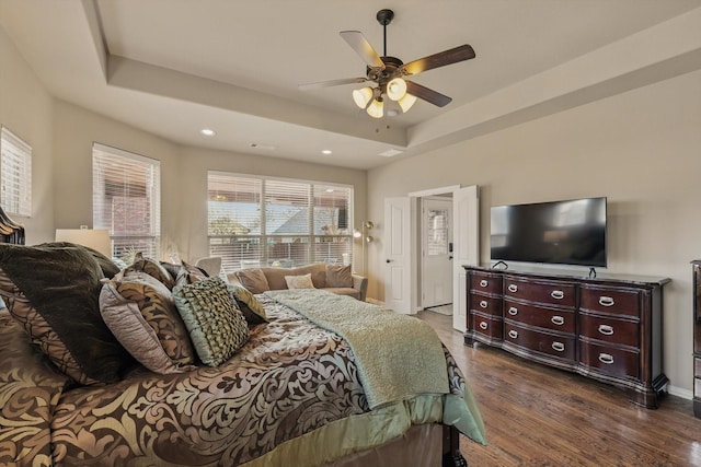 bedroom with a ceiling fan, baseboards, a tray ceiling, recessed lighting, and dark wood-type flooring