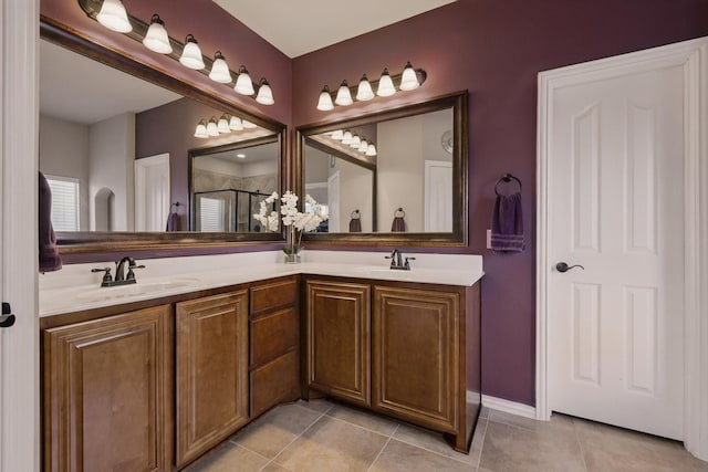 bathroom featuring tile patterned flooring, double vanity, a stall shower, and a sink