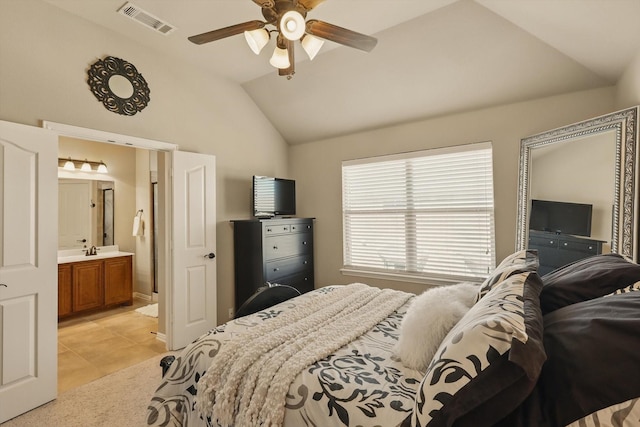 bedroom with light tile patterned floors, visible vents, a sink, vaulted ceiling, and ensuite bathroom