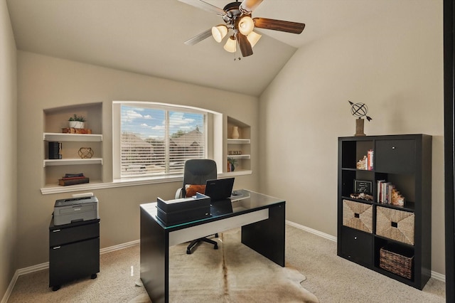 carpeted office with vaulted ceiling, built in shelves, a ceiling fan, and baseboards