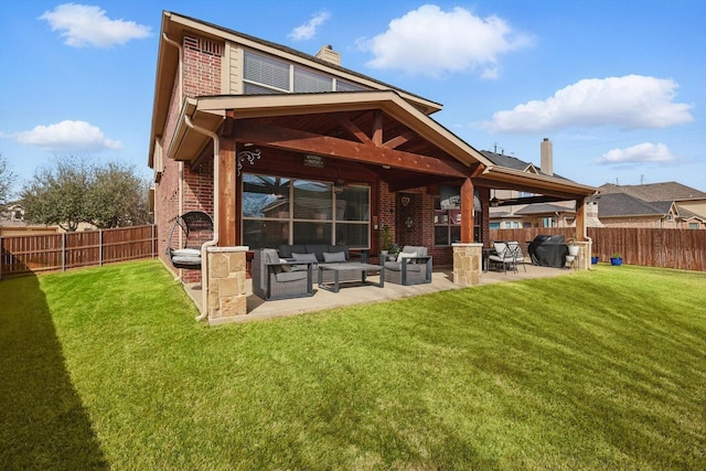 rear view of house featuring brick siding, an outdoor living space with a fireplace, a chimney, a fenced backyard, and a patio area