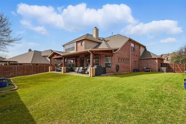 rear view of house featuring brick siding, a fenced backyard, a lawn, and a patio area