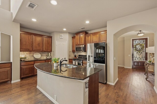 kitchen featuring visible vents, dark wood-style floors, arched walkways, stainless steel appliances, and a sink