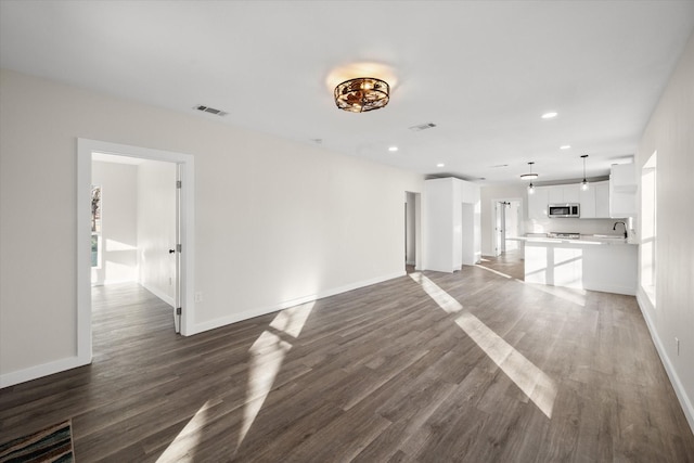 unfurnished living room with dark wood finished floors, visible vents, and baseboards