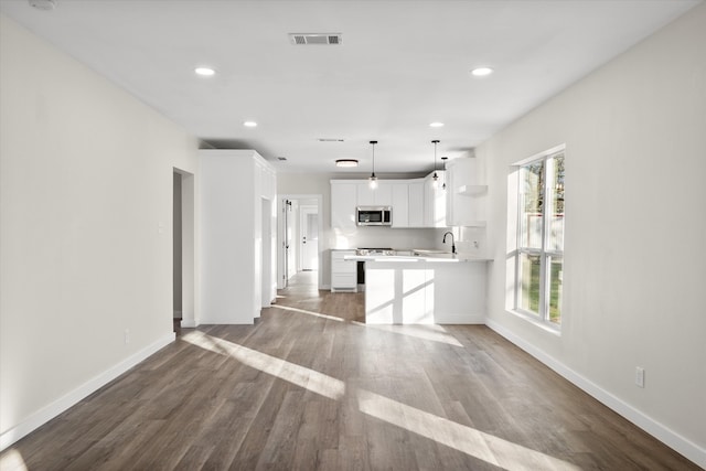 kitchen with open shelves, stainless steel microwave, wood finished floors, and a wealth of natural light