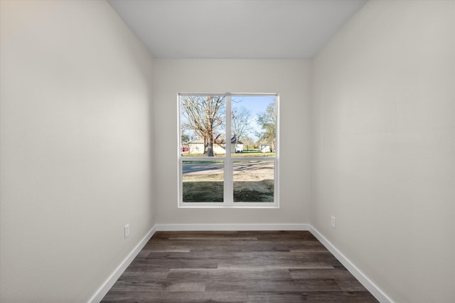 spare room featuring baseboards and dark wood-style flooring