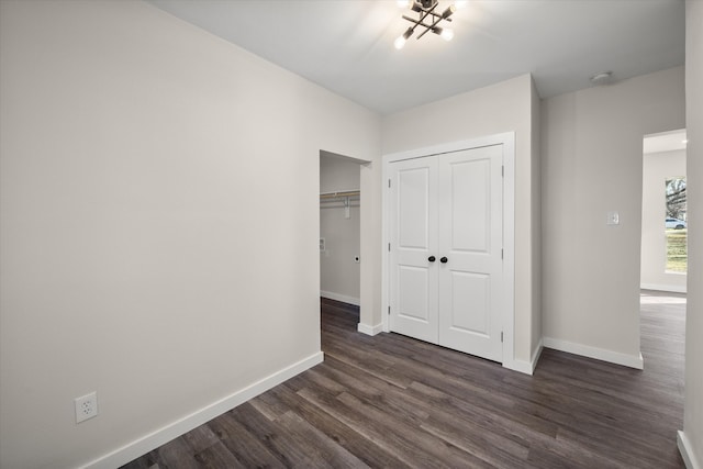 unfurnished bedroom with dark wood-type flooring, baseboards, and a closet