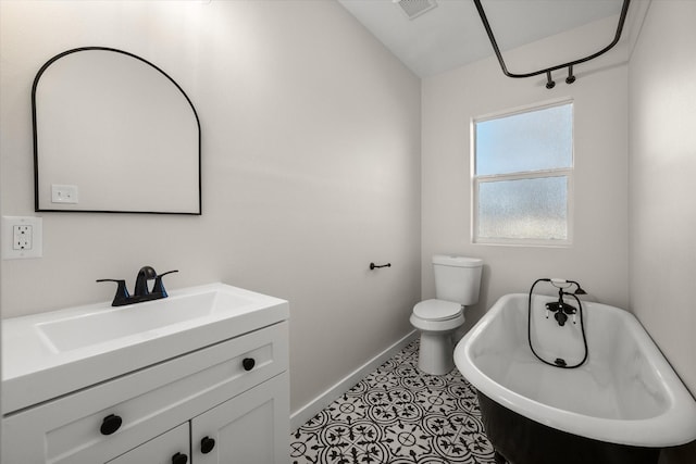 bathroom with visible vents, baseboards, toilet, a freestanding tub, and vanity