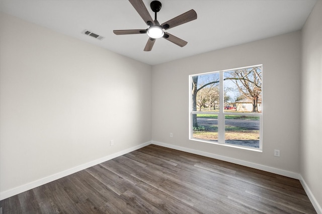 empty room featuring visible vents, dark wood-style floors, baseboards, and ceiling fan