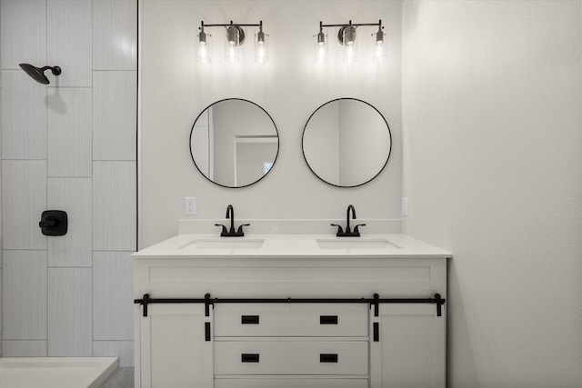 bathroom featuring a sink, tiled shower, and double vanity