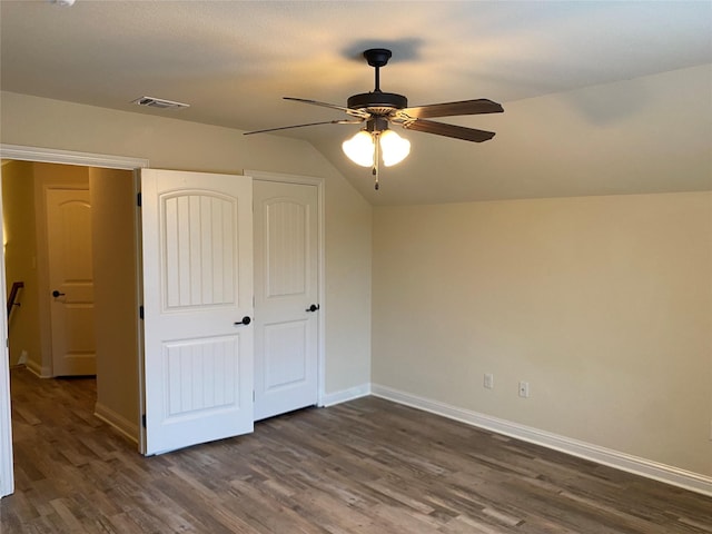 unfurnished bedroom with dark wood finished floors, vaulted ceiling, baseboards, and visible vents