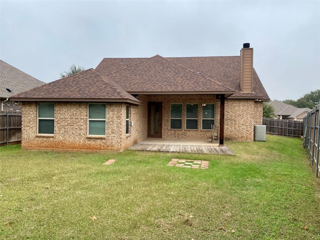 back of house with brick siding, a fenced backyard, a lawn, and a shingled roof