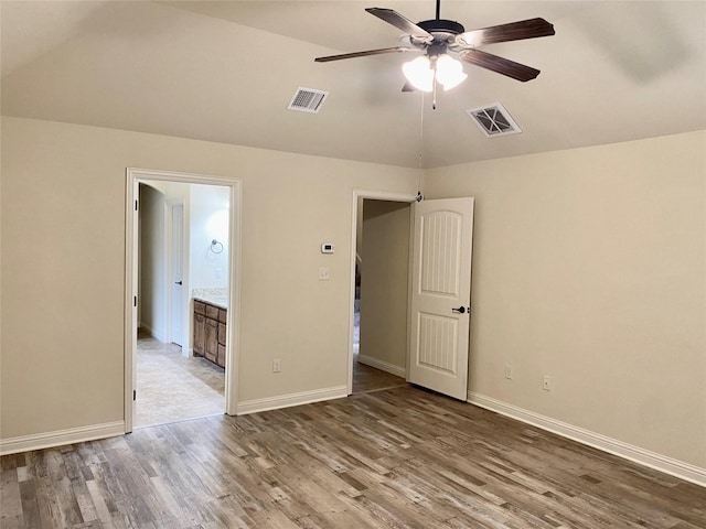 unfurnished bedroom with vaulted ceiling, wood finished floors, visible vents, and baseboards