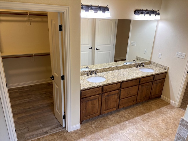 bathroom featuring a walk in closet, double vanity, and a sink