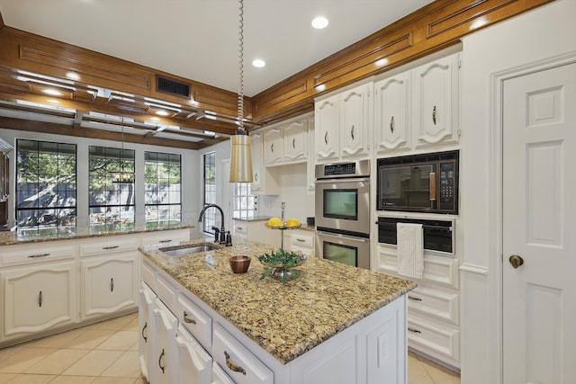 kitchen with visible vents, stainless steel double oven, an island with sink, a sink, and black microwave