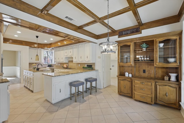 kitchen featuring visible vents, a peninsula, white cabinets, coffered ceiling, and a sink