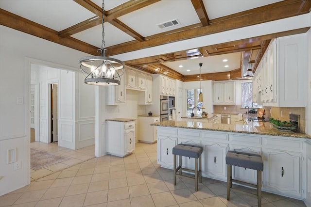 kitchen featuring visible vents, backsplash, light stone counters, appliances with stainless steel finishes, and a peninsula