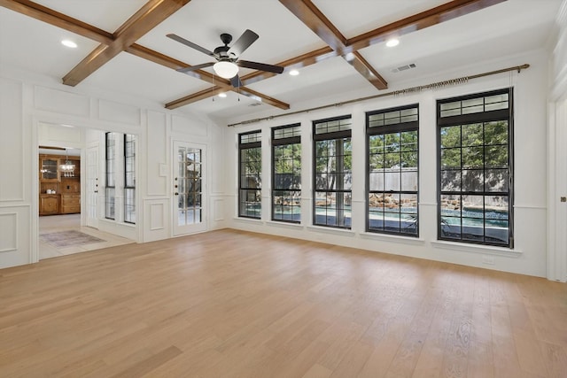 interior space featuring light wood finished floors, coffered ceiling, and a decorative wall