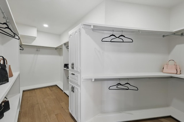 walk in closet with light wood-style floors