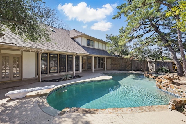 view of pool featuring a pool with connected hot tub, fence, french doors, a diving board, and a patio area