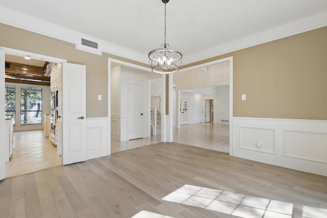 empty room featuring visible vents, light wood finished floors, and ornamental molding