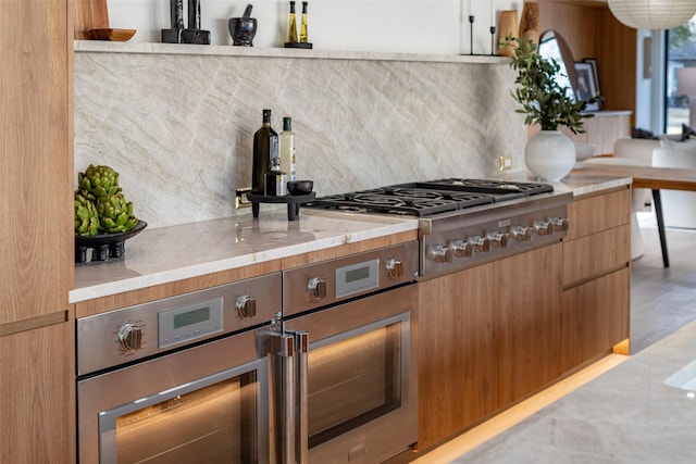 kitchen featuring decorative backsplash, appliances with stainless steel finishes, modern cabinets, and light stone countertops