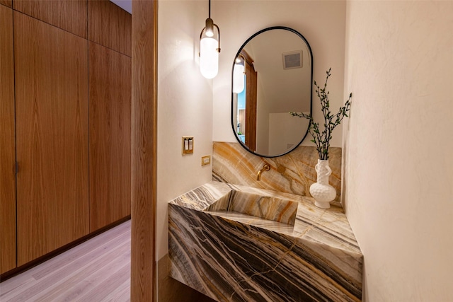 bedroom with light wood-type flooring, visible vents, and a sink