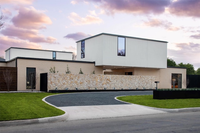 exterior space featuring stucco siding, a lawn, brick siding, and fence