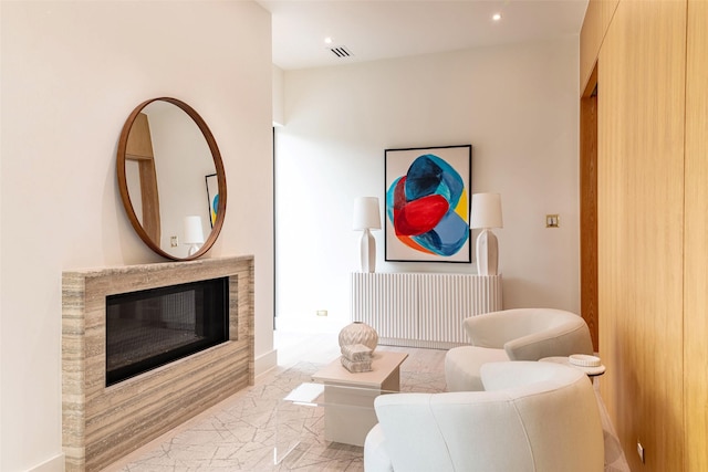 living room with recessed lighting, a glass covered fireplace, marble finish floor, and visible vents