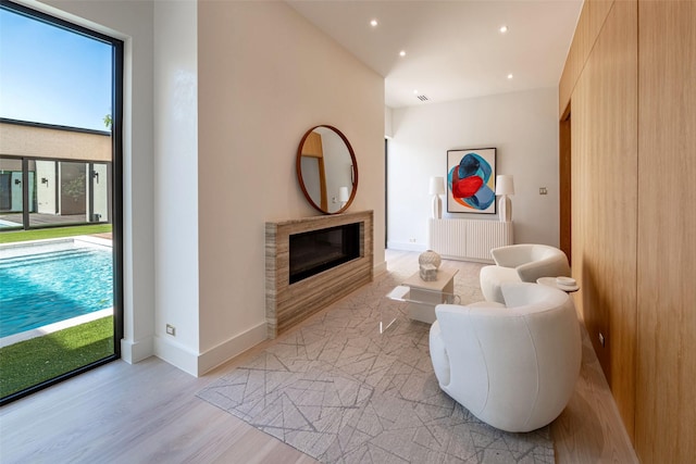 living room with recessed lighting, light wood-type flooring, baseboards, and a glass covered fireplace